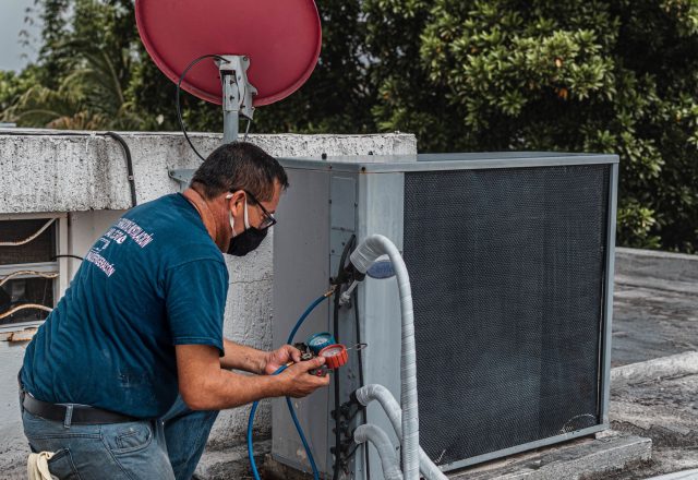 HVAC technician testing the electrical connections on an outdoor air conditioning unit