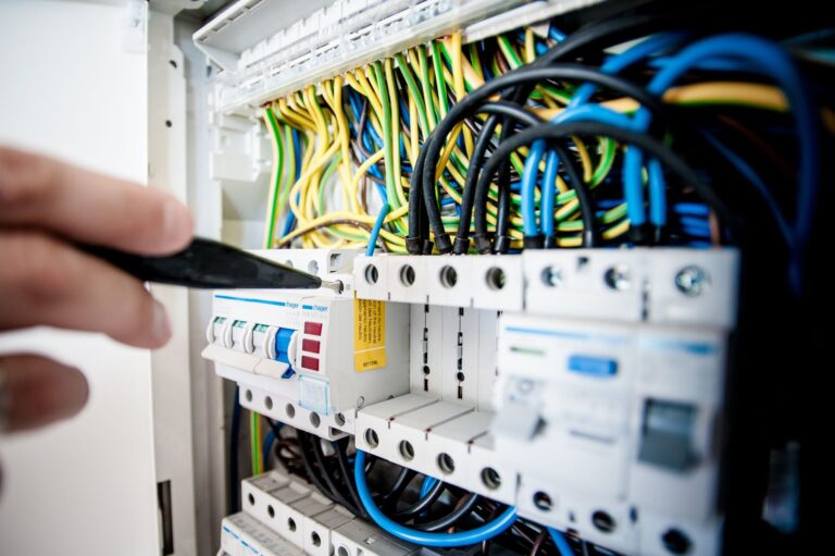 Electrician working on breakers inside an open electrical switchboard